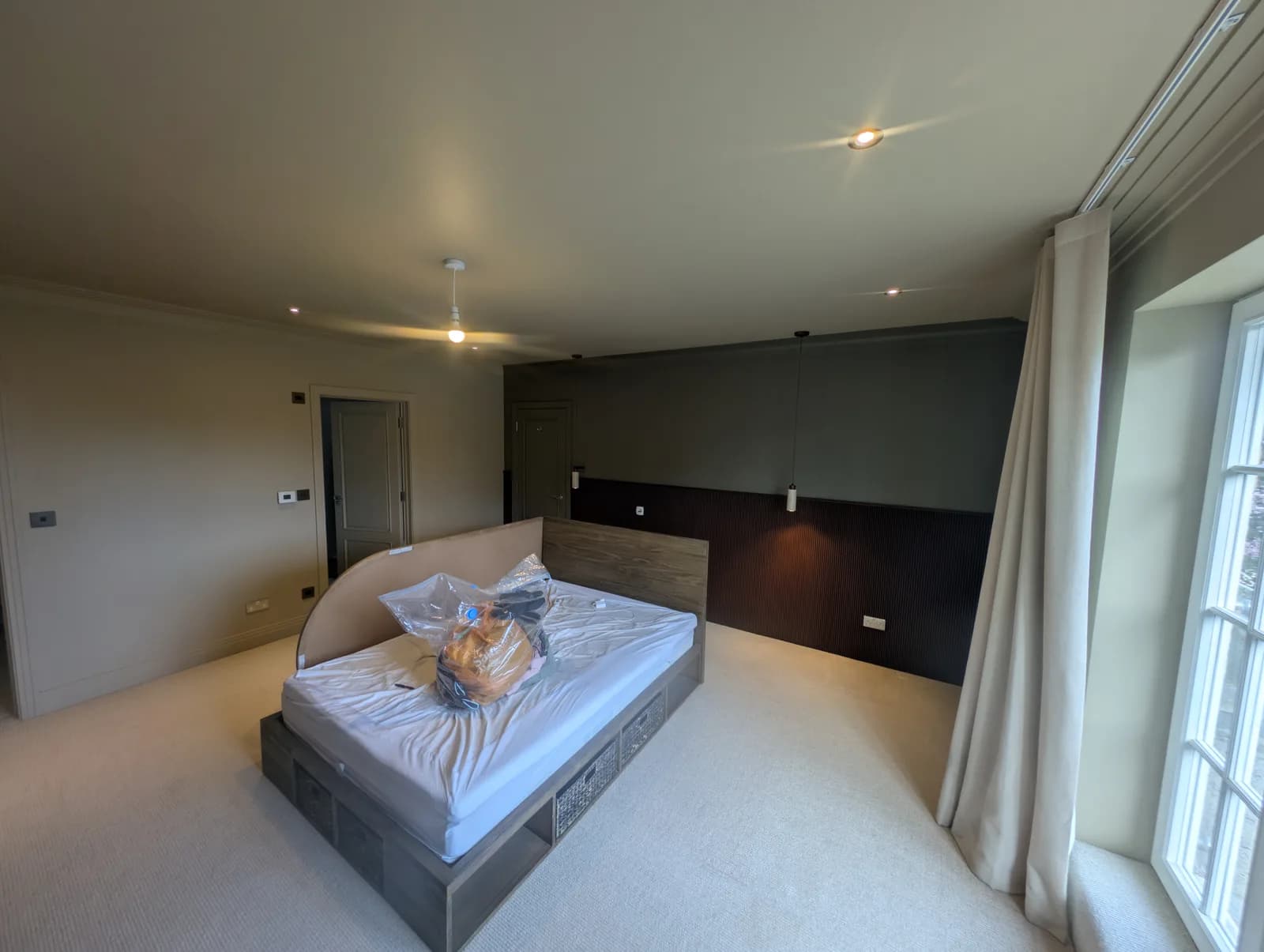 Finished loft bedroom with a dressing area, sprayed fluted panelling and a matching sideboard in a deep charcoal finish beside a walk-in window seat