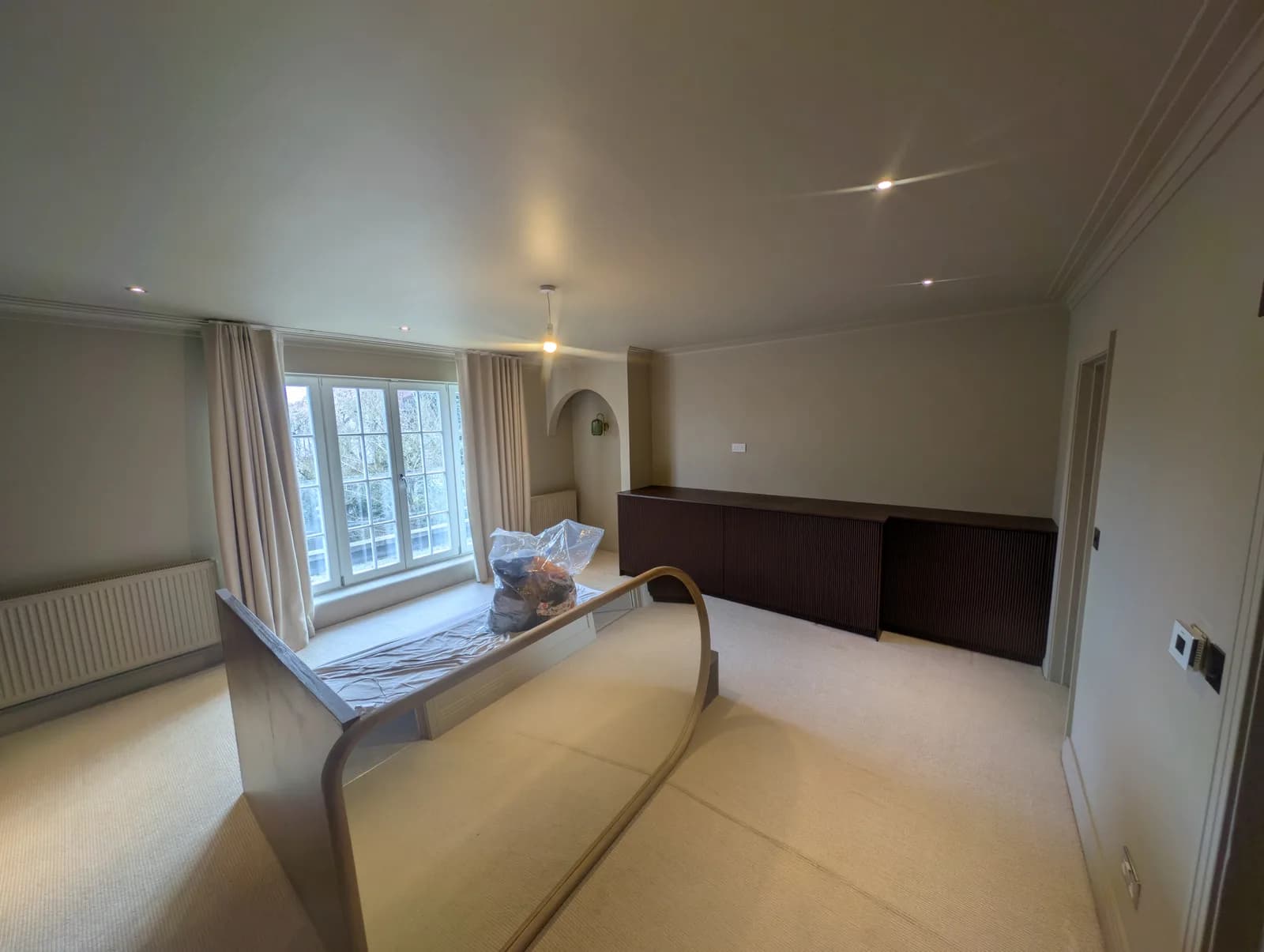 The finished bedroom from the window end, showing the sprayed panelled wall, pendant lighting and bed frame
